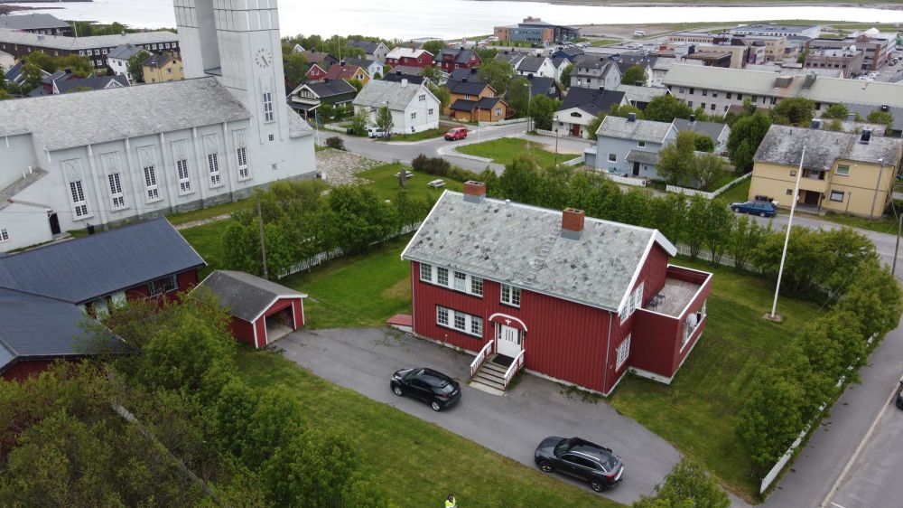 rødt trehus og kirke i droneperspektiv