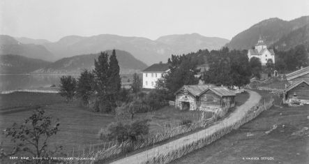 sort hvitt bilde vei, hus og kirke og fjell i bakgrunn