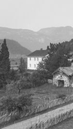 sort hvitt bilde vei, hus og kirke og fjell i bakgrunn