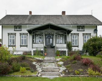 Gjerstad prestebolig. Hvitt trehus med grønne vinduskarmer og hage. Foto