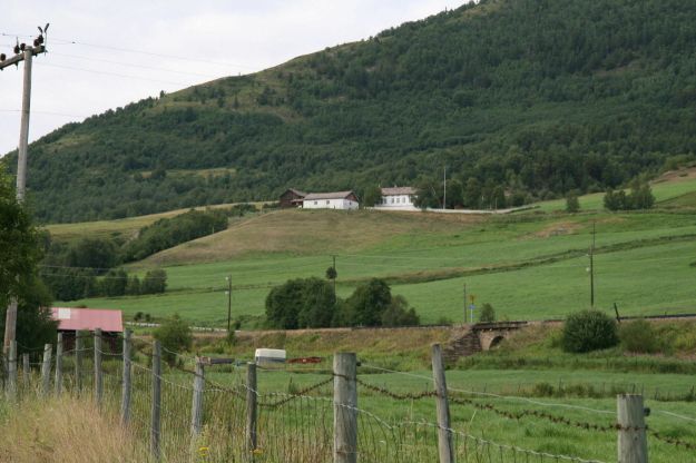 Perspektiv av prestegården i bygda med jorder foran