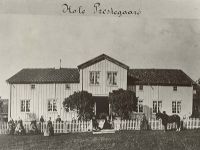 Gammelt sort hvitt foto med mennesker foran prestegården