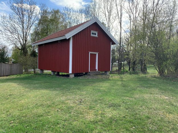 Rødt stabbur alene på gressplen