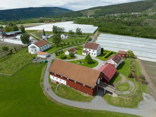 Dronebilde av gårdstun med gartneri  og kirke