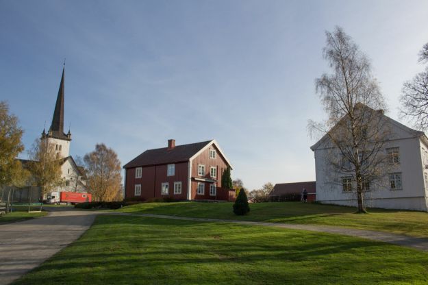 kirke, rødt forpakter hus og hvit prestegårdsbygning