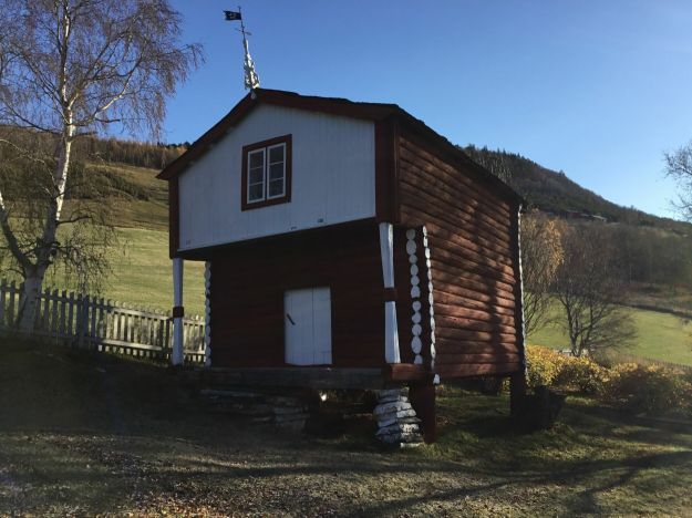 stabbur i skråning med utkraging av andre etasje