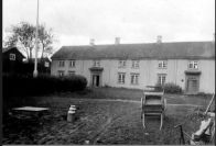 sort hvitt bilde av trønderlån med kjerre foran på tunet