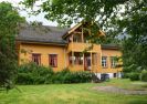okermalt sveitserhus med, veranda, ark, og gressplen foran