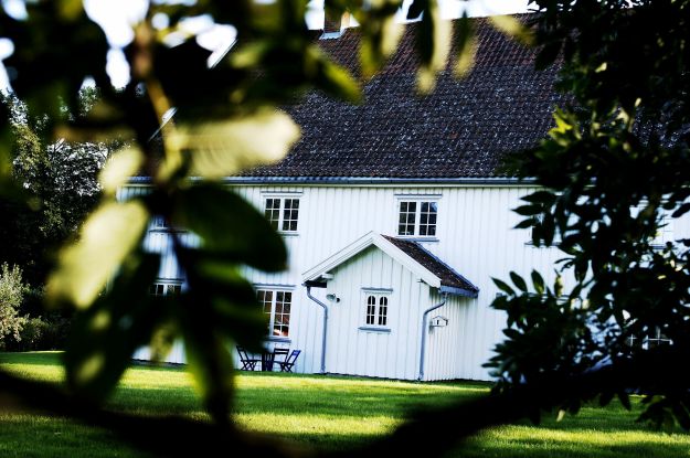 hvitt trehus til syne mellom trær