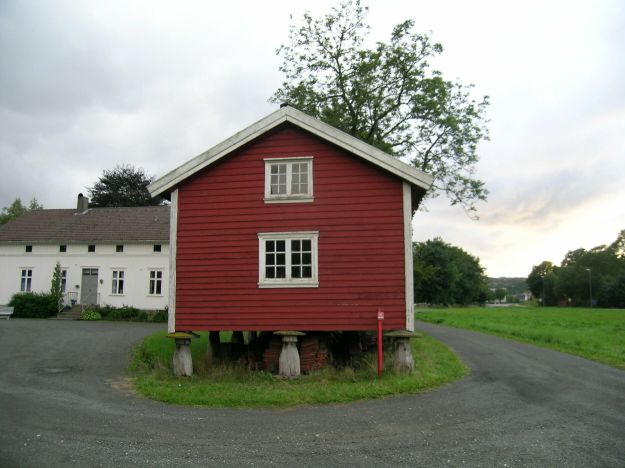 rødt stabbur og hvitt trehus i bakgrunn
