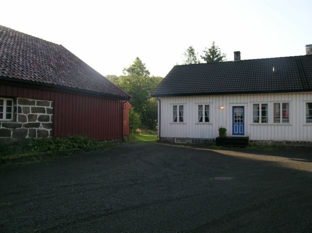 rødt stabbur og hvitt trehus i bakgrunn