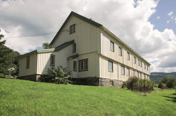 Lang trehusbygning md gressplen foran