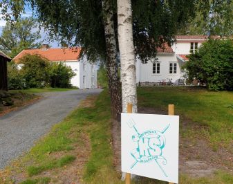 Bilde av hvitmalt våningshus med oppkjørselen i forgrunnen