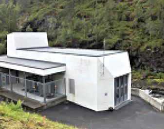 Ringdal Kraftverk. Hvitt, moderne bygg omgitt av grønn natur. Foto