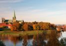 Autumn inOversiktsbilde viser Nidarosdomen omgitt av trær med høstfarger. I forgrunnen renner Nidelva.