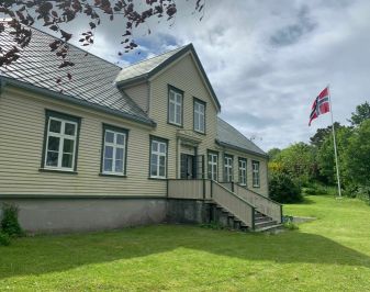 Utvendig bilde av hus med flagg i flaggstangen