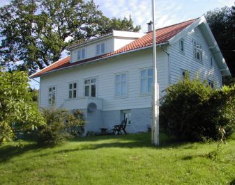 Hvitmalt trehus med hagen og flaggstang