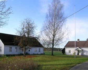 Hvit hovedbygning i tre med tuntre