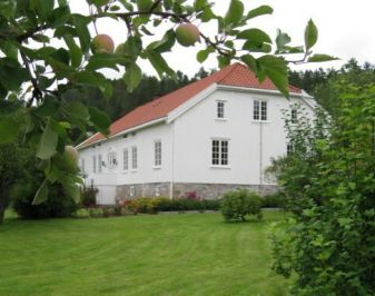 Hvitmalt trebygning med hage rundt