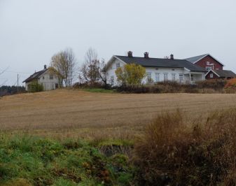 Storgård med jorde i forgrunnen, låve og våningshus