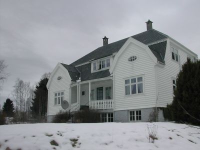 en hvit prestebolig  med to arker på vinteren med snø i forgrunn