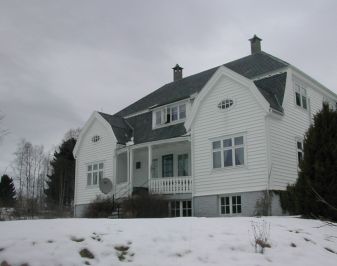 en hvit prestebolig  med to arker på vinteren med snø i forgrunn