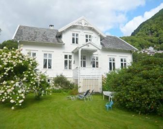 hvitt trehus med ark og grønn plen foran