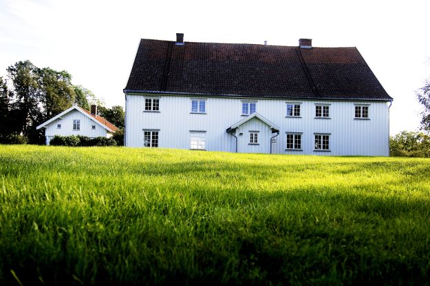 Hvit, fredet trebygning med plen i forkant