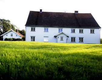 Hvit, fredet trebygning med plen i forkant