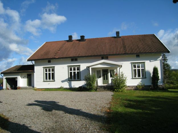 Hvitt trehus på tun med grønnmalt dør og vinduer