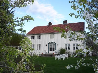 Hvitmalt hus med hage i forgrunnen