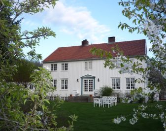 Hvitmalt hus med hage i forgrunnen