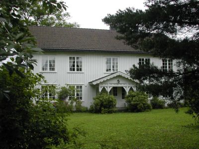 Stort hvitt hus med hagen i forgrunnen