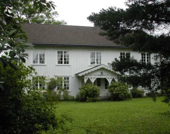 Stort hvitt hus med hagen i forgrunnen