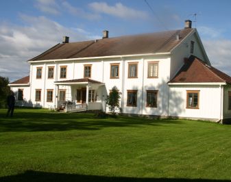 Storslått hvitmalt bygning med parkmessig hage