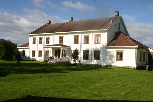 Storslått hvitmalt bygning med parkmessig hage