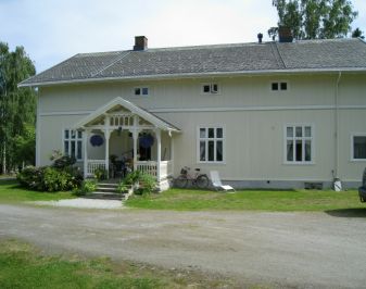 Hvitmalt stort trehus med tunet i forkant