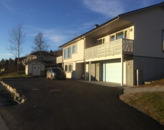 Foto av nyere prestebolig tatt på kvelden, med skygge på bakken.