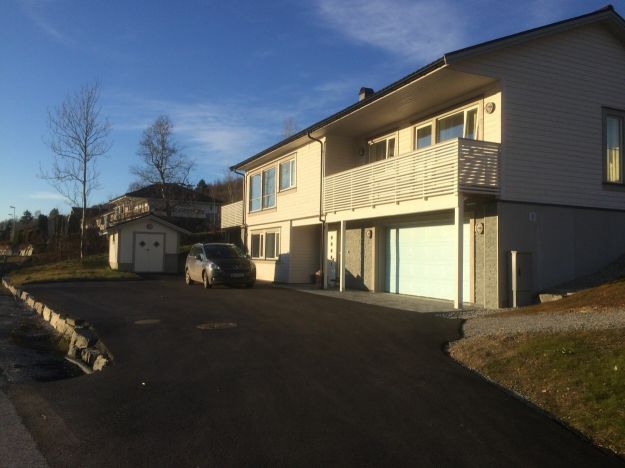 Foto av nyere prestebolig tatt på kvelden, med skygge på bakken.