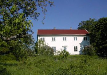 Hvit trebygning med stor hage i forgrunnen