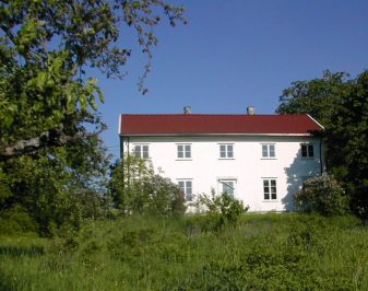 Hvit trebygning med stor hage i forgrunnen