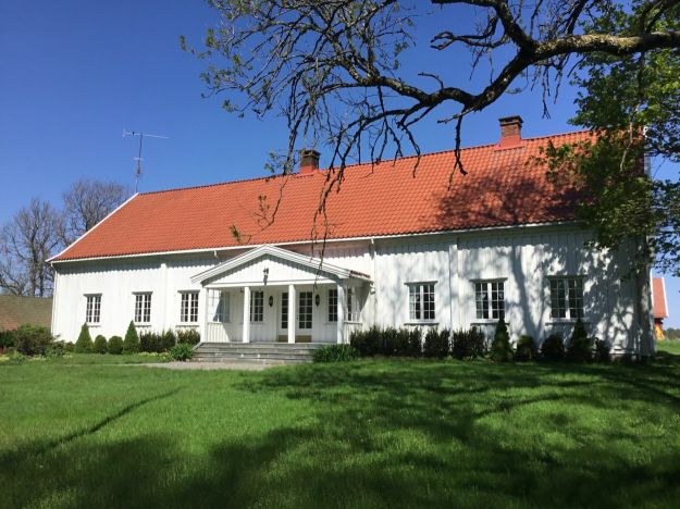 Hvit hovedbygning med stor plen i forkant