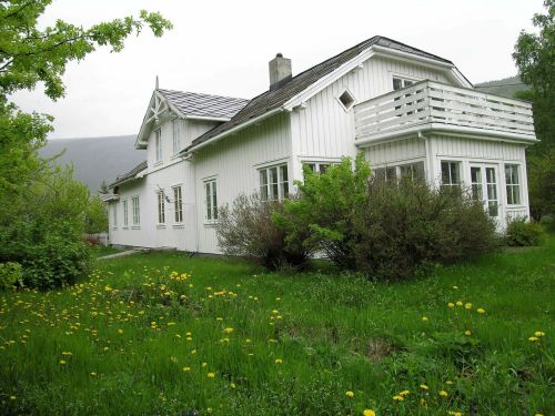 Hvitmalt prestebolig med veranda gressplen i forkant