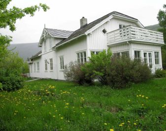 Hvitmalt prestebolig med veranda gressplen i forkant