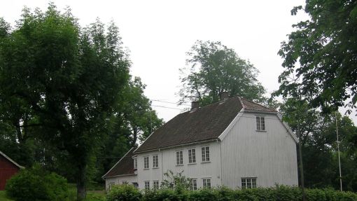 Hvitt stor trehus med hekk rundt