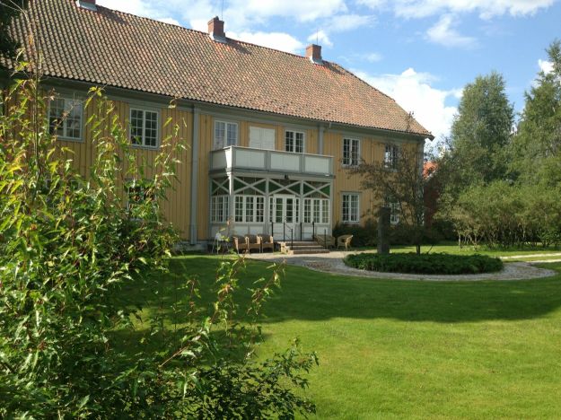 Gulmalt trebygning med parkmessig hage rundt