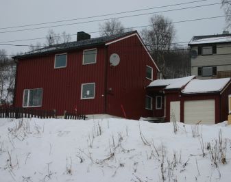 Nyere rødt trehus i vinterlandskap