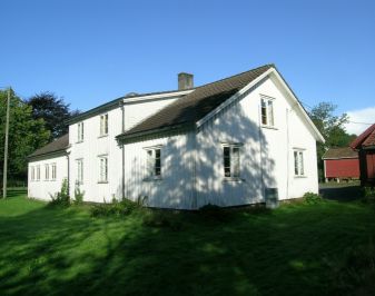 Hvitmalt stort trehus med hage