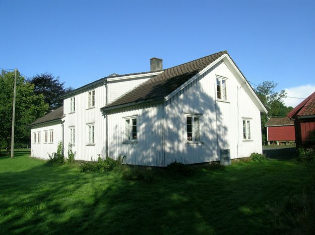 Hvitmalt stort trehus med hage