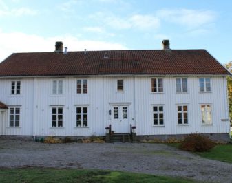 Stor, hvit trebygning med tun i forkant